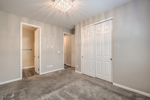 unfurnished bedroom featuring carpet flooring, a chandelier, a closet, and baseboards