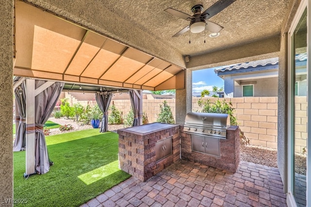 view of patio with grilling area, an outdoor kitchen, and ceiling fan