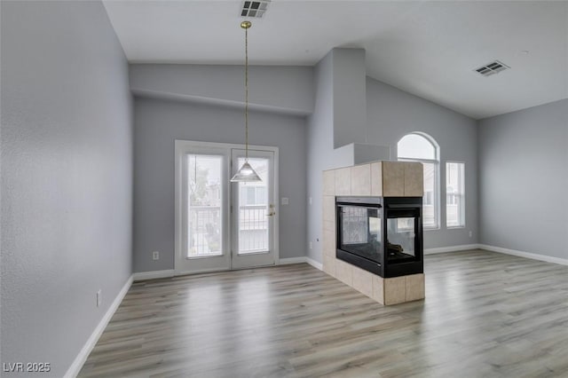 8675 Traveling Breeze Ave Unit 101, Las Vegas, NV 89178 - unfurnished living room with wood finished floors, baseboards, a tile fireplace, and high vaulted ceiling