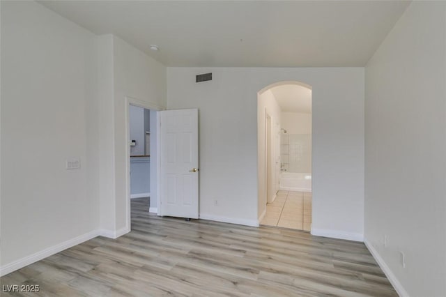 8675 Traveling Breeze Ave Unit 101, Las Vegas, NV 89178 - unfurnished room with arched walkways, light wood-style flooring, and baseboards