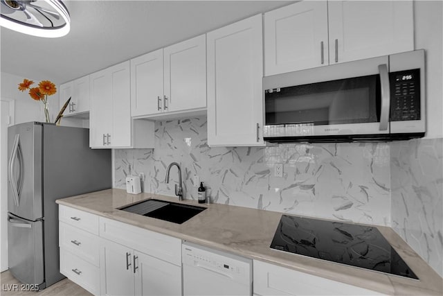 kitchen with appliances with stainless steel finishes, a sink, white cabinets, and decorative backsplash