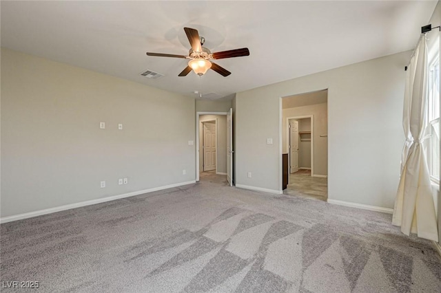 unfurnished bedroom with light colored carpet, baseboards, ceiling fan, and a spacious closet