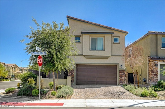 view of front of house with stucco siding, stone siding, an attached garage, and decorative driveway