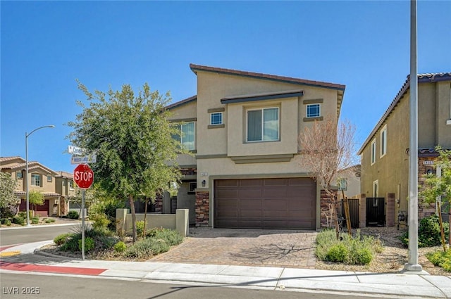 townhome / multi-family property featuring stucco siding, an attached garage, decorative driveway, and fence