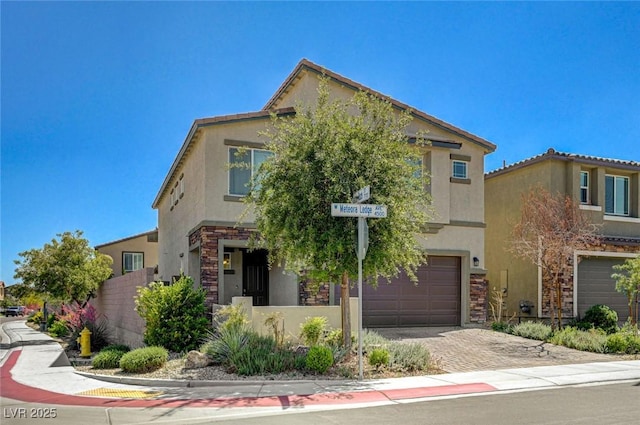 view of front of house featuring stucco siding, an attached garage, stone siding, driveway, and fence