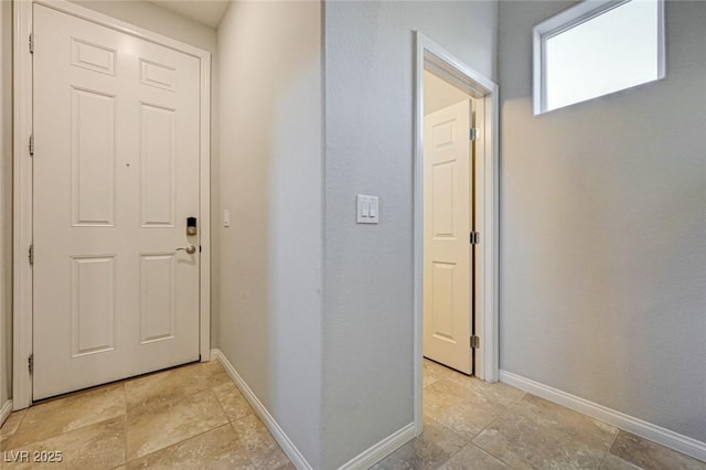 entrance foyer featuring baseboards and light stone finish floors