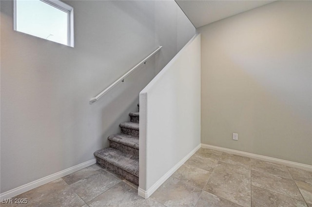staircase featuring stone finish floors and baseboards