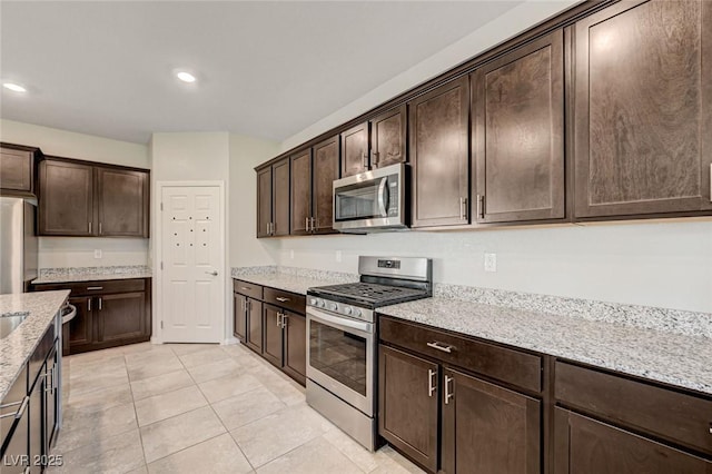 kitchen featuring appliances with stainless steel finishes, dark brown cabinets, light stone counters, light tile patterned floors, and recessed lighting