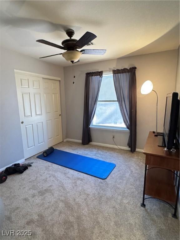 workout room with carpet flooring, a ceiling fan, and baseboards