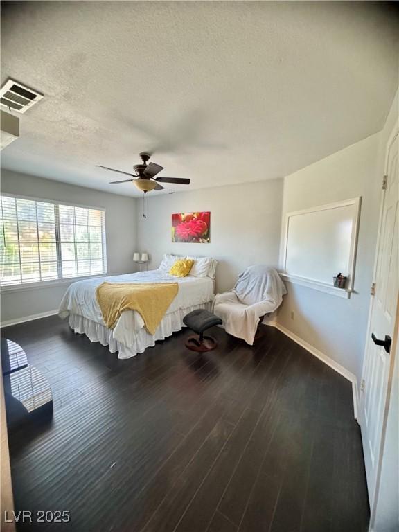 bedroom featuring baseboards, wood finished floors, a ceiling fan, and a textured ceiling