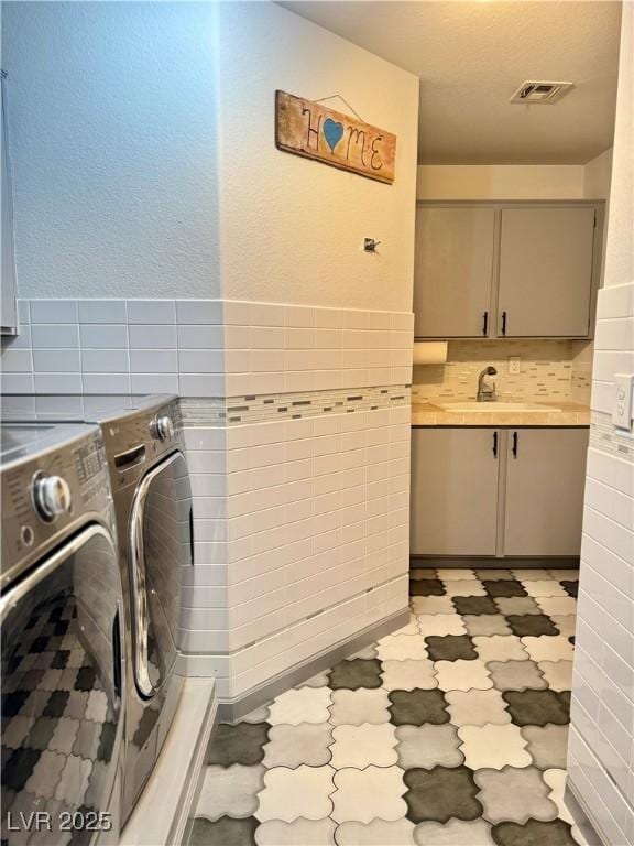 laundry room with cabinet space, independent washer and dryer, tile walls, and light floors