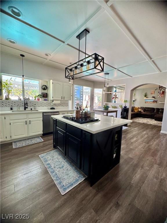 kitchen with dishwasher, a sink, light countertops, dark wood-type flooring, and plenty of natural light