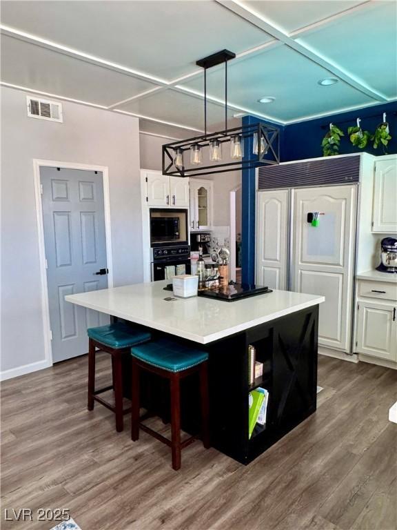 kitchen with built in appliances, white cabinetry, a kitchen island, and dark wood-type flooring
