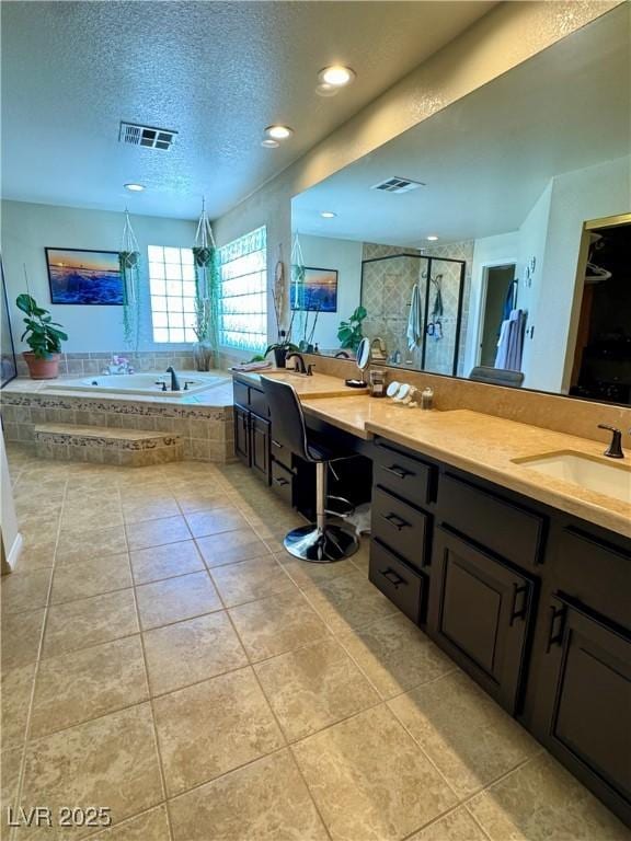 full bath featuring a bath, tile patterned flooring, a stall shower, vanity, and a textured ceiling