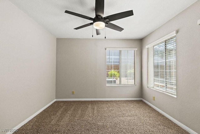 carpeted empty room with plenty of natural light, a ceiling fan, and baseboards