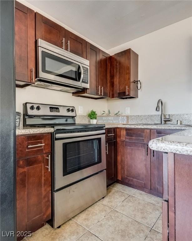 kitchen featuring stainless steel appliances, light tile patterned floors, and light stone countertops