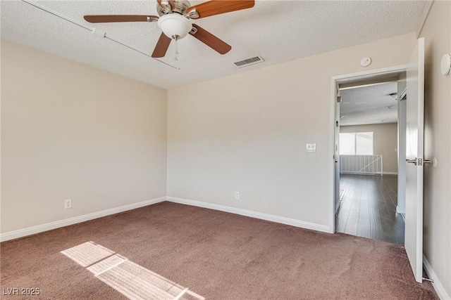 carpeted empty room featuring a ceiling fan, a textured ceiling, baseboards, and a smoke detector