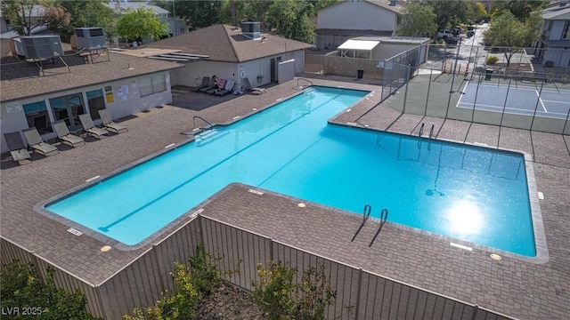 community pool with central AC unit, fence, and a patio