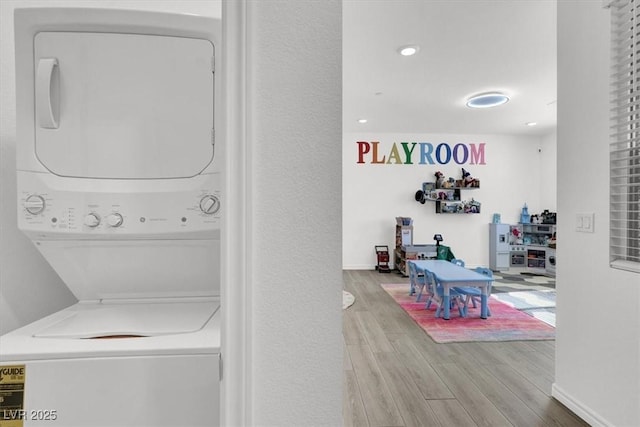laundry area featuring estacked washer and dryer and wood finished floors
