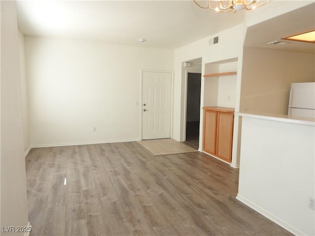 9470 Peace Way Unit 112, Las Vegas, NV 89147 - empty room featuring a chandelier, light wood-style floors, and baseboards