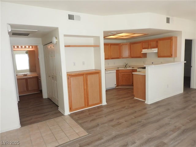 9470 Peace Way Unit 112, Las Vegas, NV 89147 - kitchen with white dishwasher, light wood-type flooring, a sink, light countertops, and under cabinet range hood