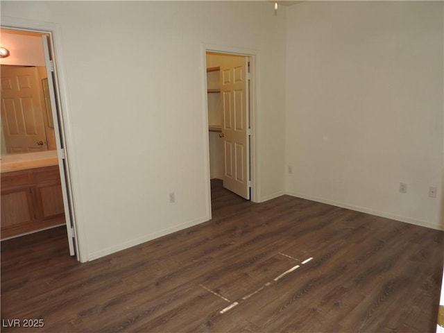 9470 Peace Way Unit 112, Las Vegas, NV 89147 - unfurnished bedroom featuring a spacious closet, dark wood-style flooring, baseboards, ensuite bathroom, and a closet
