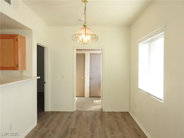 9470 Peace Way Unit 112, Las Vegas, NV 89147 - unfurnished dining area with a chandelier, light wood-type flooring, and baseboards