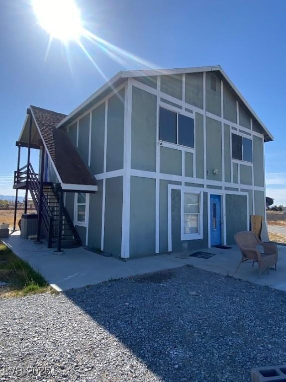 4910 Elizabeth St, Pahrump, NV 89048 - back of house with stairway, a patio, stucco siding, and a sunroom