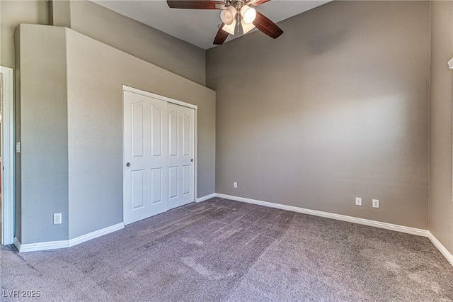 unfurnished bedroom with dark colored carpet, baseboards, a closet, and a high ceiling
