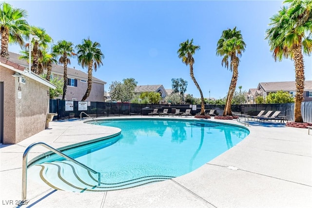 community pool with fence, a patio, and a residential view