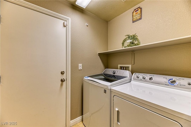 clothes washing area with washer and dryer and a textured wall