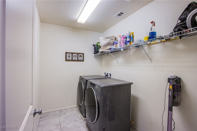 washroom with washer and clothes dryer, light tile patterned floors, and baseboards