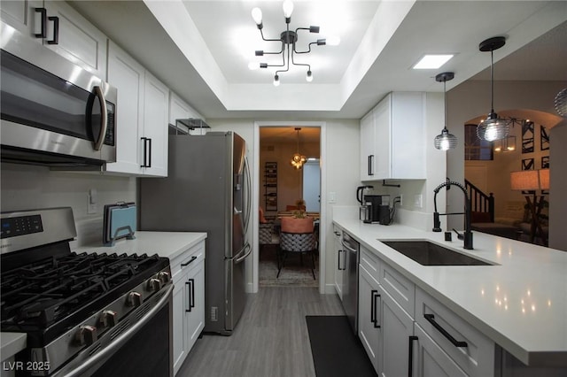 9013 Cypress Point Way, Las Vegas, NV 89117 - kitchen with stainless steel appliances, a chandelier, a sink, a peninsula, and a tray ceiling