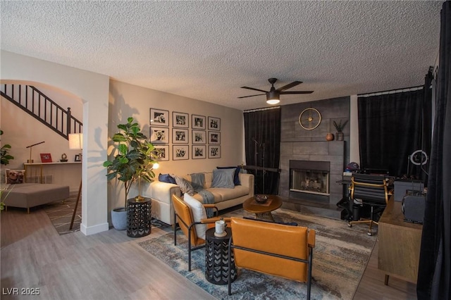 9013 Cypress Point Way, Las Vegas, NV 89117 - living room featuring wood finished floors, ceiling fan, a textured ceiling, a fireplace, and stairway