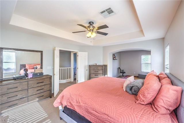 1213 High Altitude Ave, North Las Vegas, NV 89032 - bedroom featuring a raised ceiling, light colored carpet, arched walkways, and a ceiling fan