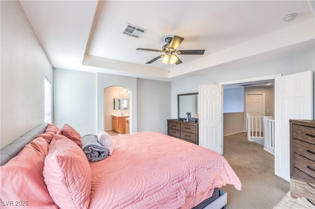 1213 High Altitude Ave, North Las Vegas, NV 89032 - bedroom featuring arched walkways, light carpet, a tray ceiling, ensuite bath, and ceiling fan