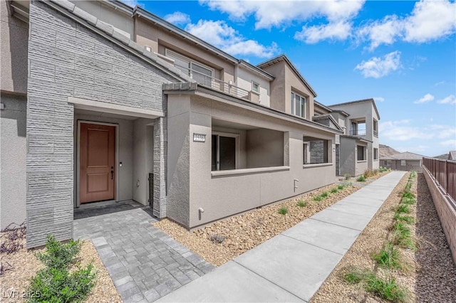 doorway to property with stucco siding, fence, and a residential view