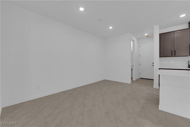 unfurnished living room with recessed lighting and baseboards