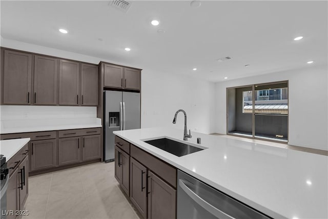 kitchen with a sink, stainless steel appliances, light countertops, dark brown cabinets, and recessed lighting