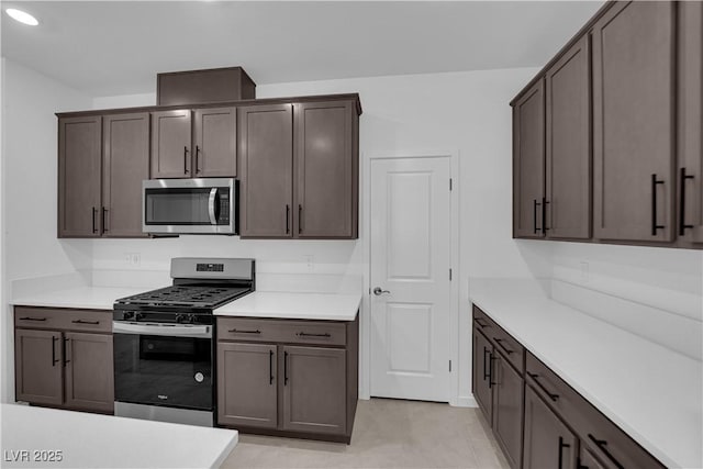 kitchen featuring stainless steel appliances, dark brown cabinetry, and light countertops