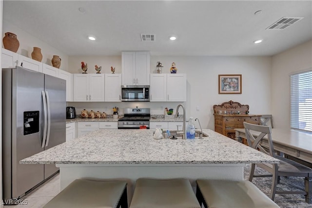 387 Larksong Ave, Henderson, NV 89011 - kitchen featuring appliances with stainless steel finishes, a kitchen breakfast bar, white cabinets, light stone counters, and recessed lighting
