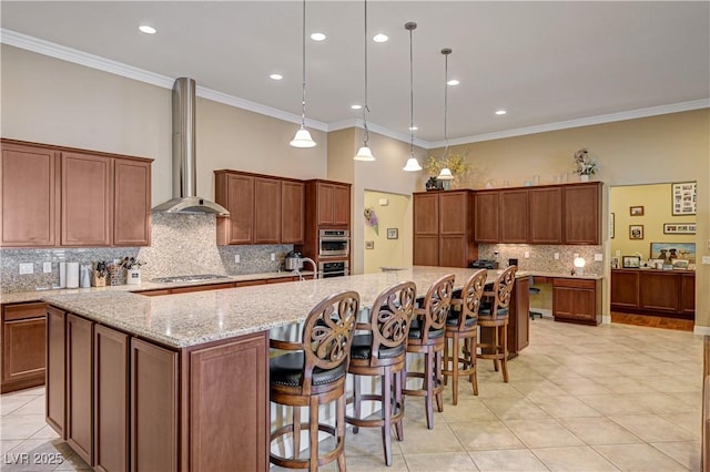 kitchen featuring wall chimney range hood, light tile patterned flooring, tasteful backsplash, a spacious island, and ornamental molding