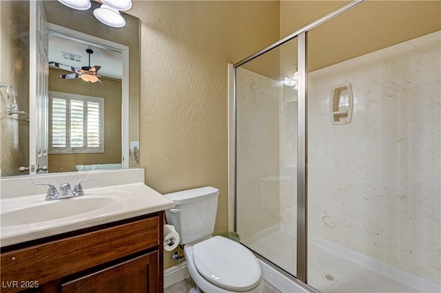 full bath featuring a stall shower, toilet, a textured wall, vanity, and a ceiling fan