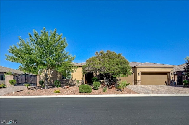 obstructed view of property with stucco siding, an attached garage, decorative driveway, a gate, and fence
