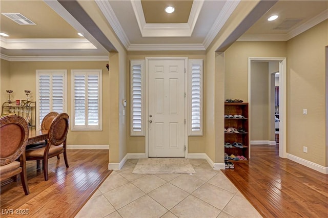 foyer entrance featuring light wood-style floors, crown molding, and baseboards