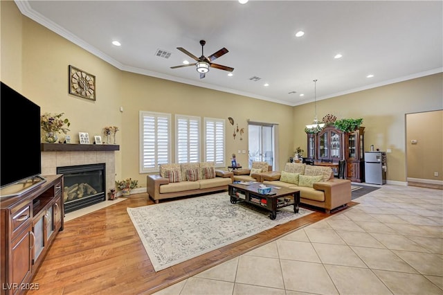 living room featuring recessed lighting, ornamental molding, ceiling fan, a tiled fireplace, and baseboards