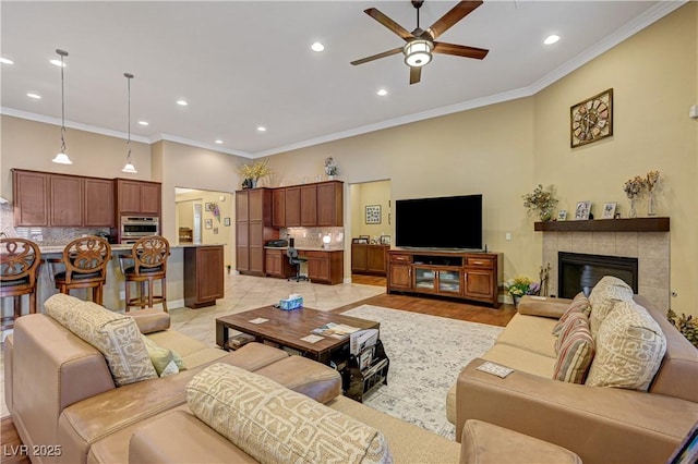 living room with ornamental molding, ceiling fan, recessed lighting, a fireplace, and baseboards