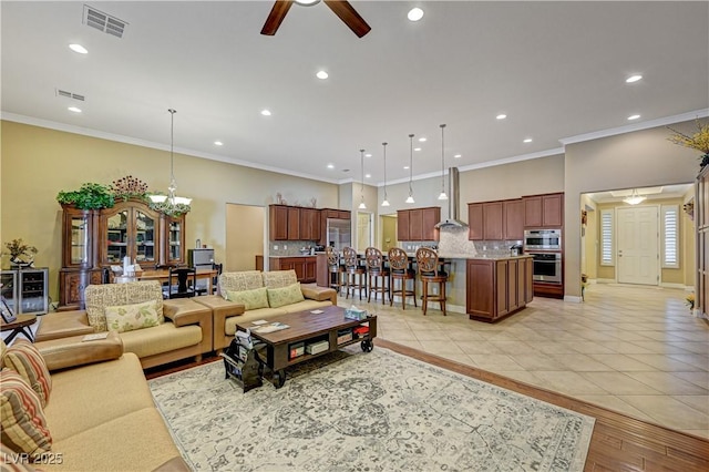 living room featuring ceiling fan, recessed lighting, a chandelier, ornamental molding, and light tile patterned flooring