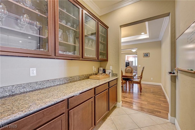 bar area with ornamental molding, light tile patterned floors, and baseboards