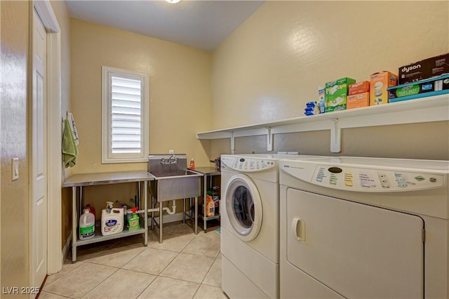 clothes washing area with washer and dryer and light tile patterned floors